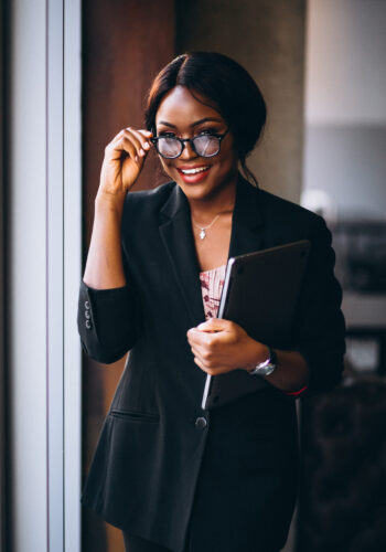 African american business woman holding laptop and standing by the window